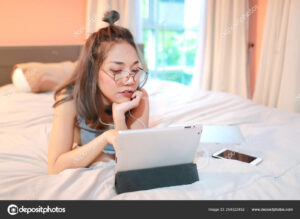 Young attractive businesswoman in glasses writing in a red notepad, sitting in front of the laptop in a cafe. 4